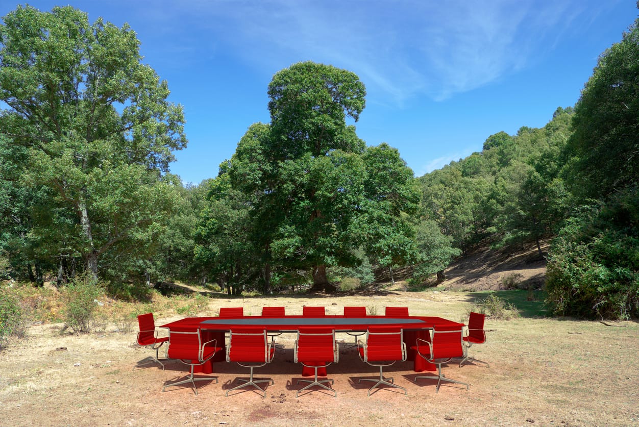 une table et des chaises de salle de formation placées dans une clairière en pleine forêt