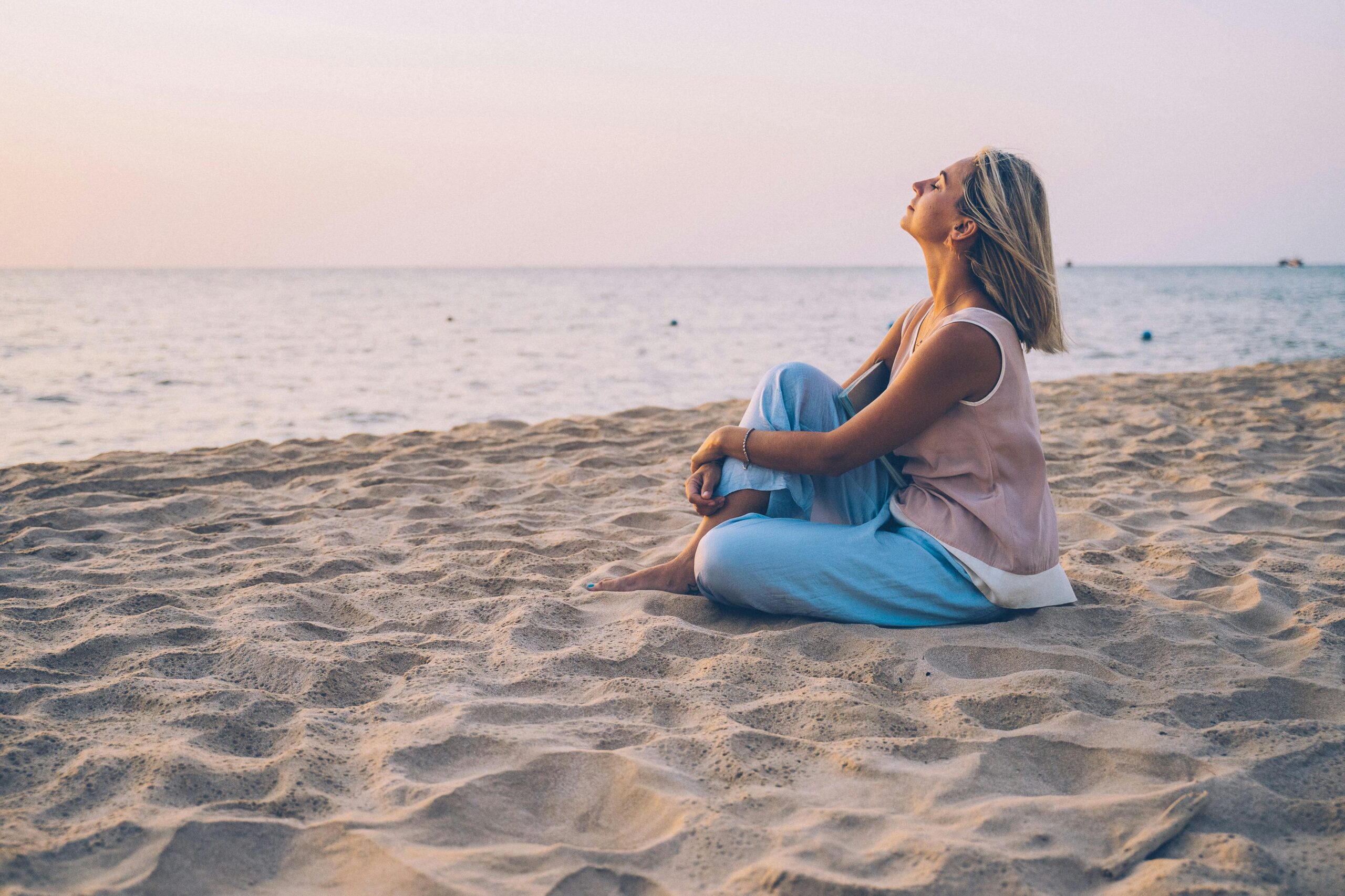 femme pratiquant le remplacement de la pensée sur une plage pour retrouver un état intérieur de bien-être et un niveau d'énergie élevé